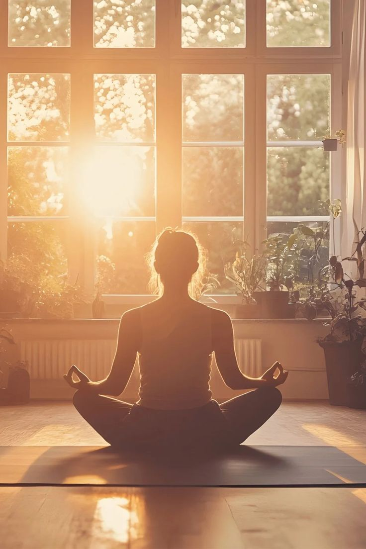 Persona in meditazione davanti a una finestra illuminata dal sole